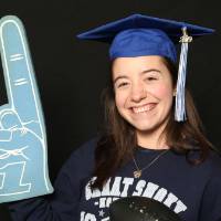 woman in graduation cap with foam finger and football